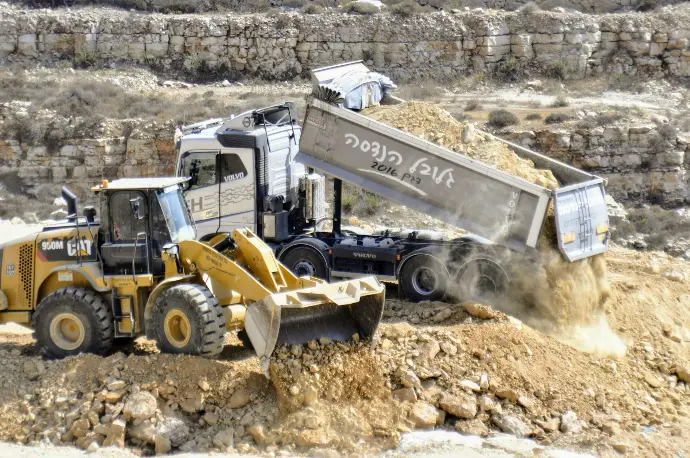 a dump truck dumping dirt into a pile